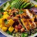 Nahaufnahme eines Mango-Hühnchensalats in einer Schüssel, mit frischen Zutaten.