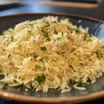 Nahaufnahme von Basmati Reis mit Zitronenscheiben und frischen Kräutern.