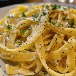 Nahaufnahme von cremiger Zitronenpasta mit frischen Kräutern.