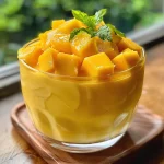 Primer plano de un postre de mango con yogur, presentado en un plato.