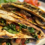 Nahaufnahme von veganen Quesadillas mit Spinat und schmelzendem Käse.