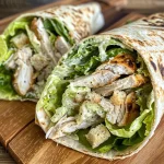 Nahaufnahme eines Chicken Caesar Wraps mit frischem Salat und Parmesan.