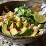 ['A vibrant close-up of a bowl filled with Aguacate con Pollo, showcasing diced avocados and shredded chicken.', 'A side view of a delicious Aguacate con Pollo, featuring fresh ingredients like avocado and chicken.', 'Juicy Aguacate con Pollo presented in a bowl, highlighting the green avocados and tender chicken pieces.', 'Close-up of Aguacate con Pollo, with visible chunks of avocado, chicken, and colorful vegetables.']